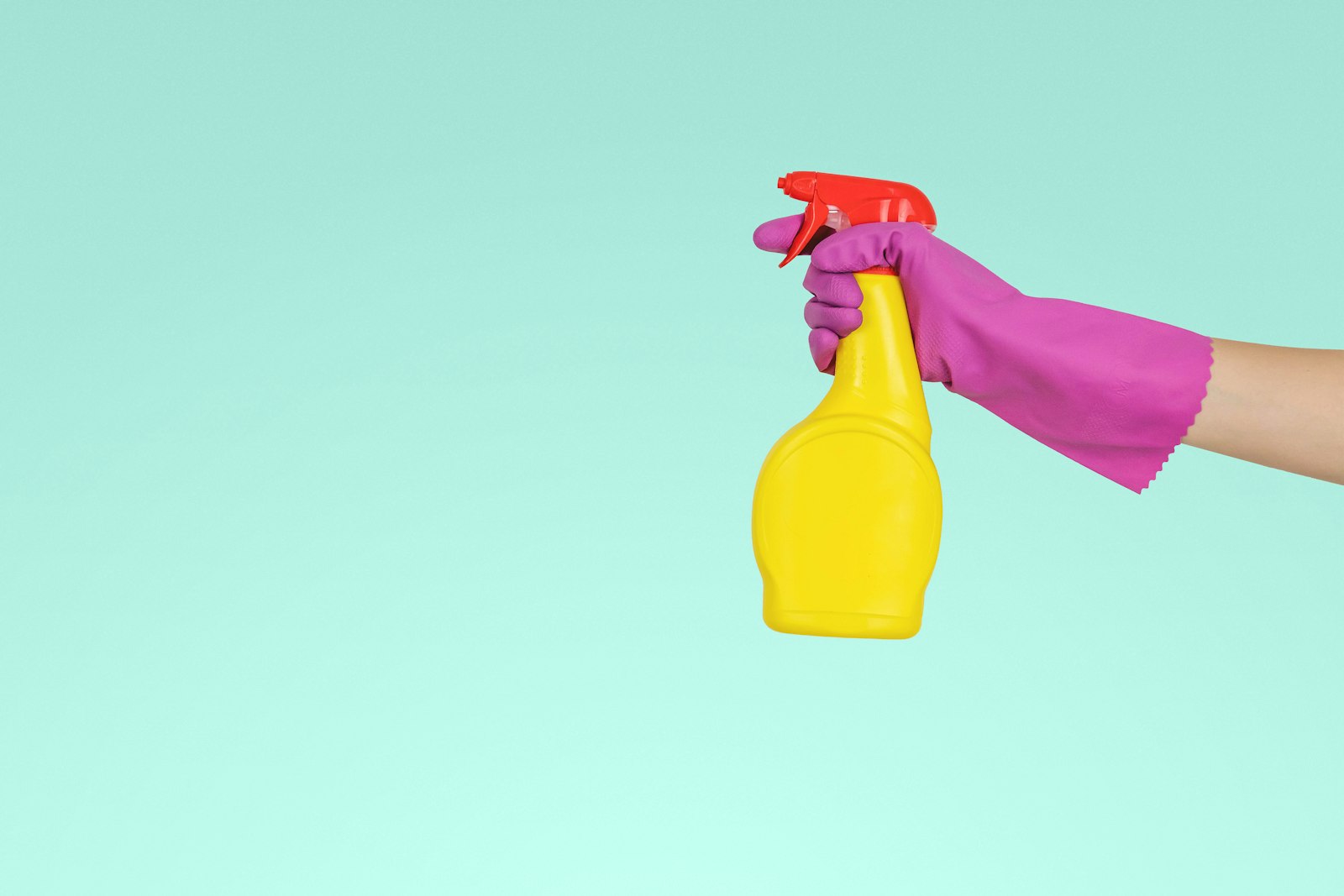 Gloved hand holding a spray bottle of cleaning solution