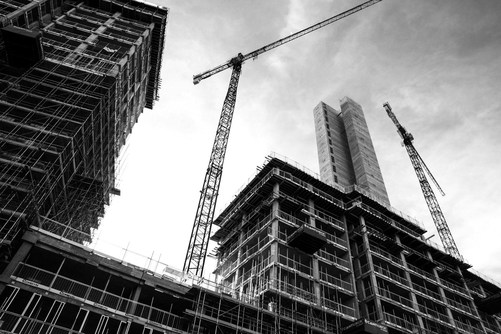 Construction crane working above a building frame on an active site